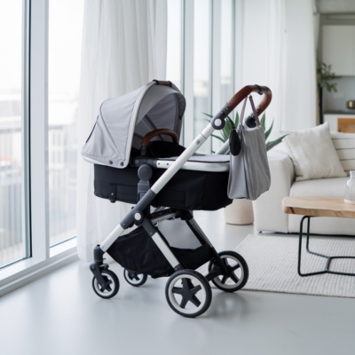 Compact gray stroller with a bassinet attachment and leather-accented handle, perfectly suited for small apartment spaces and urban living.